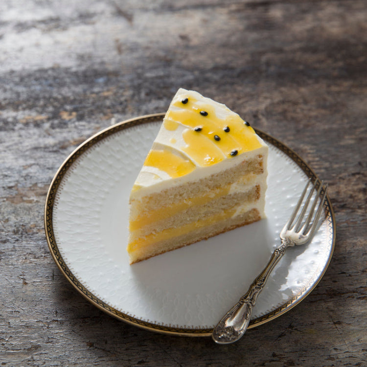 Slice of layered Passion Fruit Cake with lemon curd on a plate with a fork, on a wooden surface