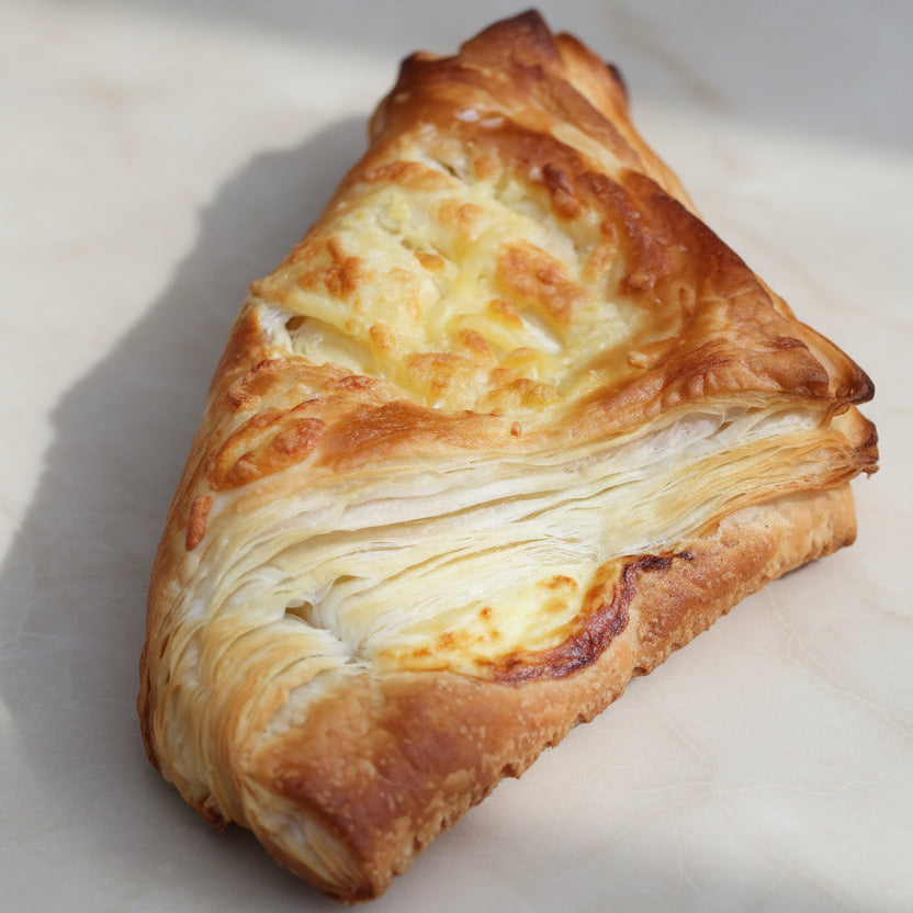 Freshly baked cheese puffs with golden, flaky layers on a baking tray