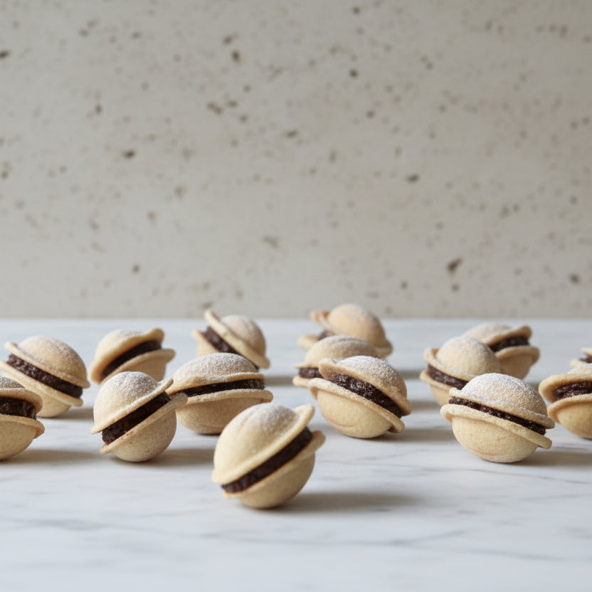 Handmade Romanian walnut-shaped cookies with buttery biscuit shells and chocolate walnut rum filling, sold in bags of 11 from North London bakery
