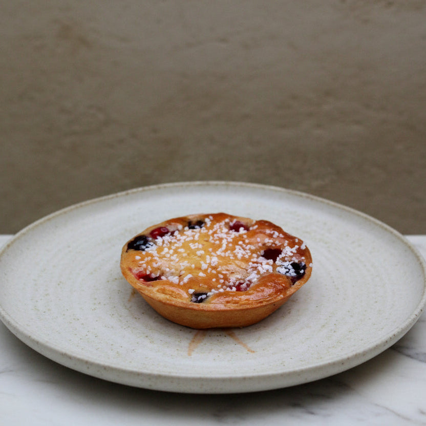 Mixed berries frangipane tart with golden pastry, almond cream, and fresh strawberries, raspberries, and blueberries, handmade in North London