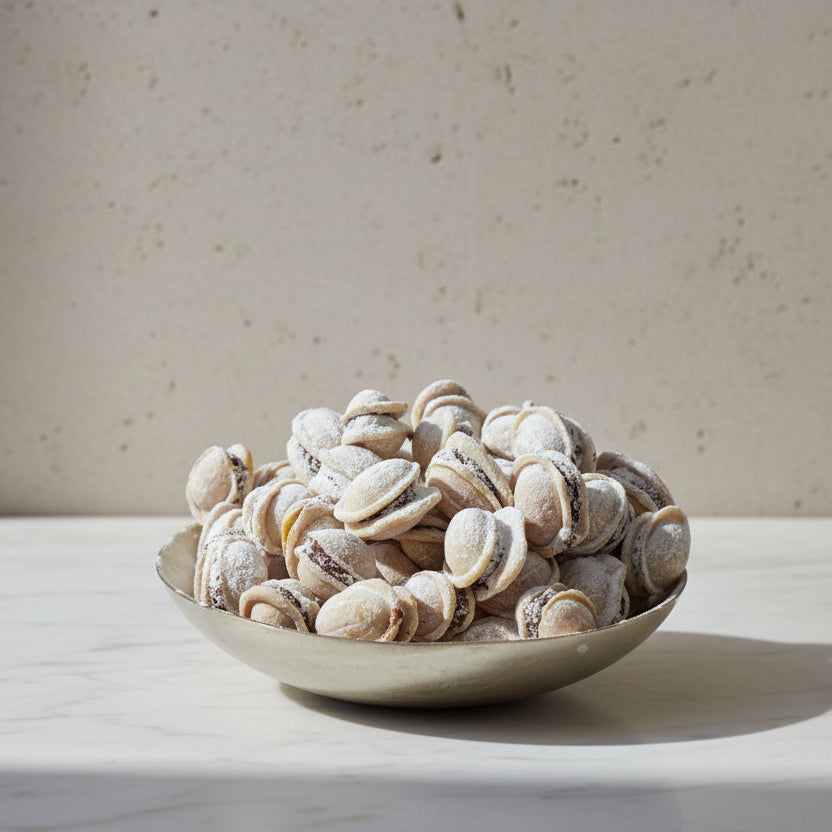 Romanian Walnut Cookies filled with chocolate, rum, honey, and crushed walnuts, dusted with icing sugar made in North London.